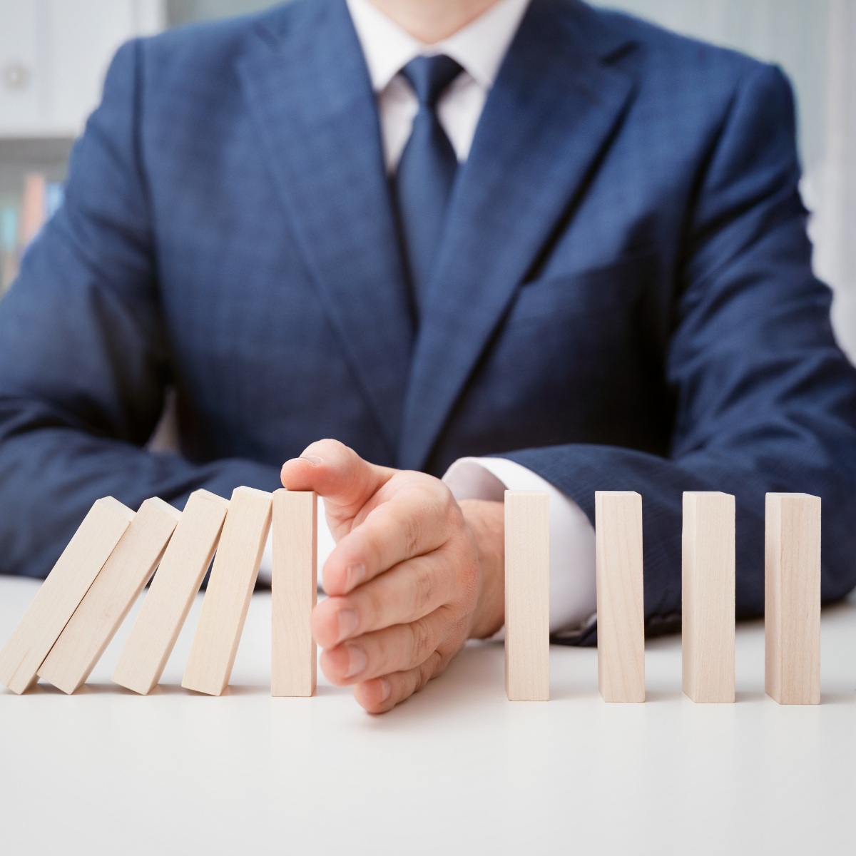Nahaufnahme eines Managers, der Holzklötze umstößt, als Symbol für Souveränität in Krise